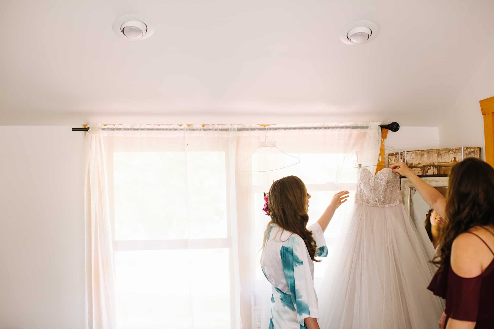 bride getting ready, bride with sister, bride with maid of honor, bride putting on dress, floral robe bride
