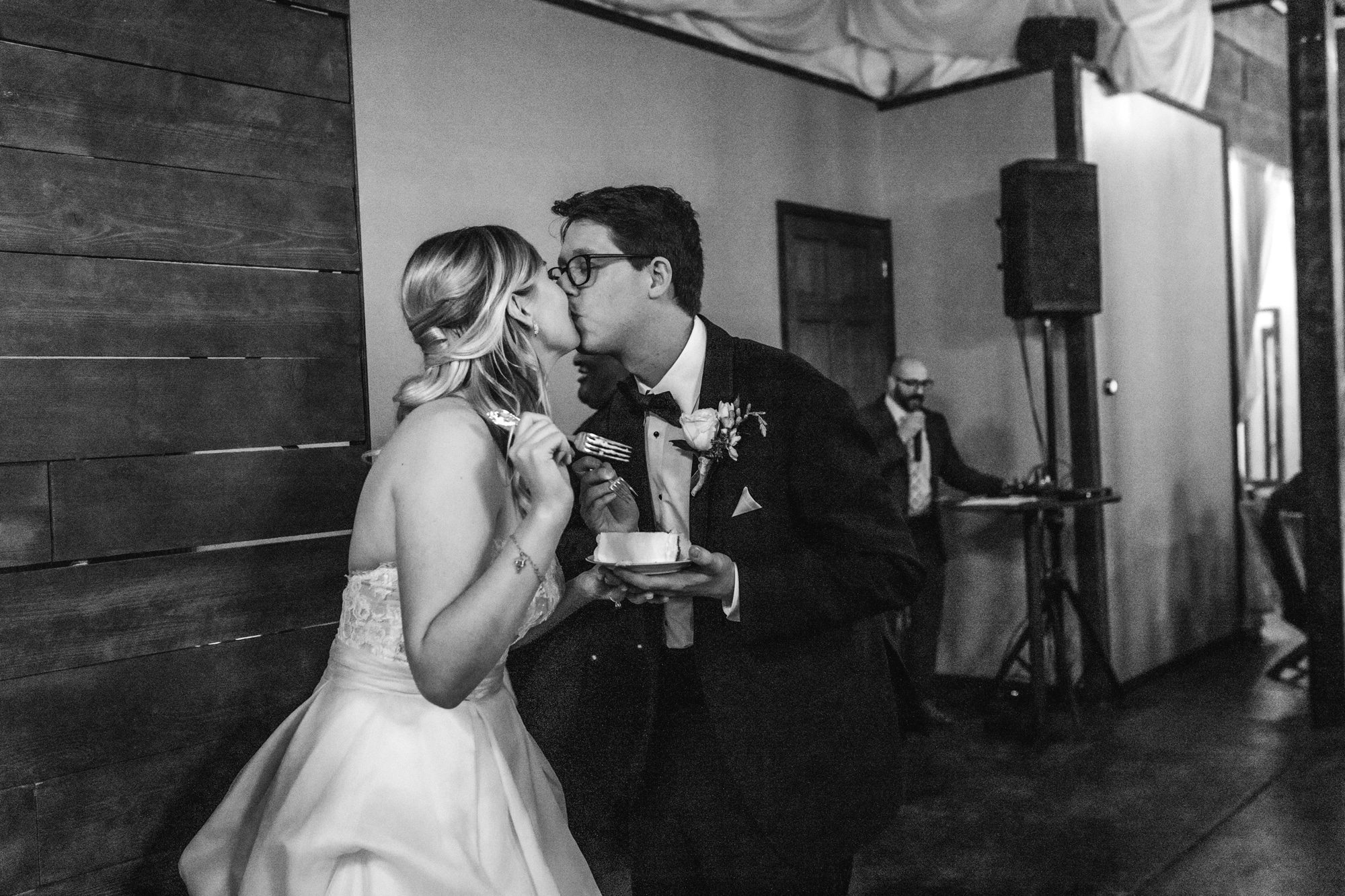 indoor wedding reception, industrial wedding venue, black and white wedding, bride and groom cutting cake, groom with glasses
