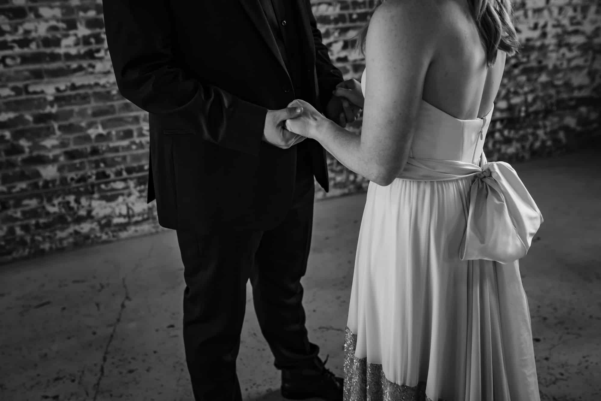 black and white wedding, bride and groom holding hands, wedding dress tie in the back, holding hands