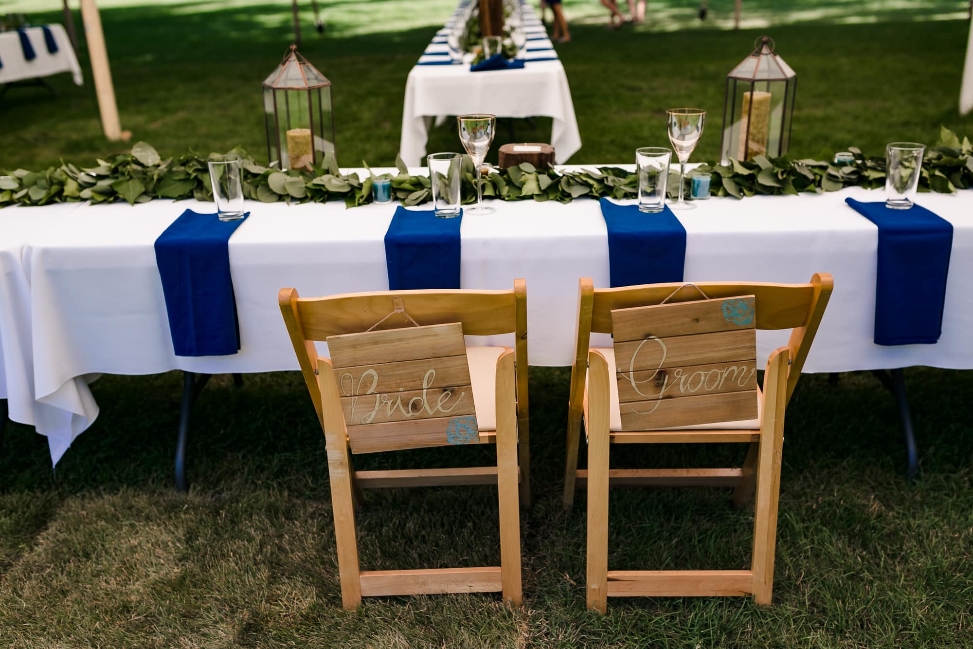 wood decor at wedding, floral table runner, eucalyptus table runner, blue and white wedding, simple wedding decor, backyard wedding, tent wedding, blue and green wedding, outdoor wedding, outdoor wedding reception, outdoor wedding dinner