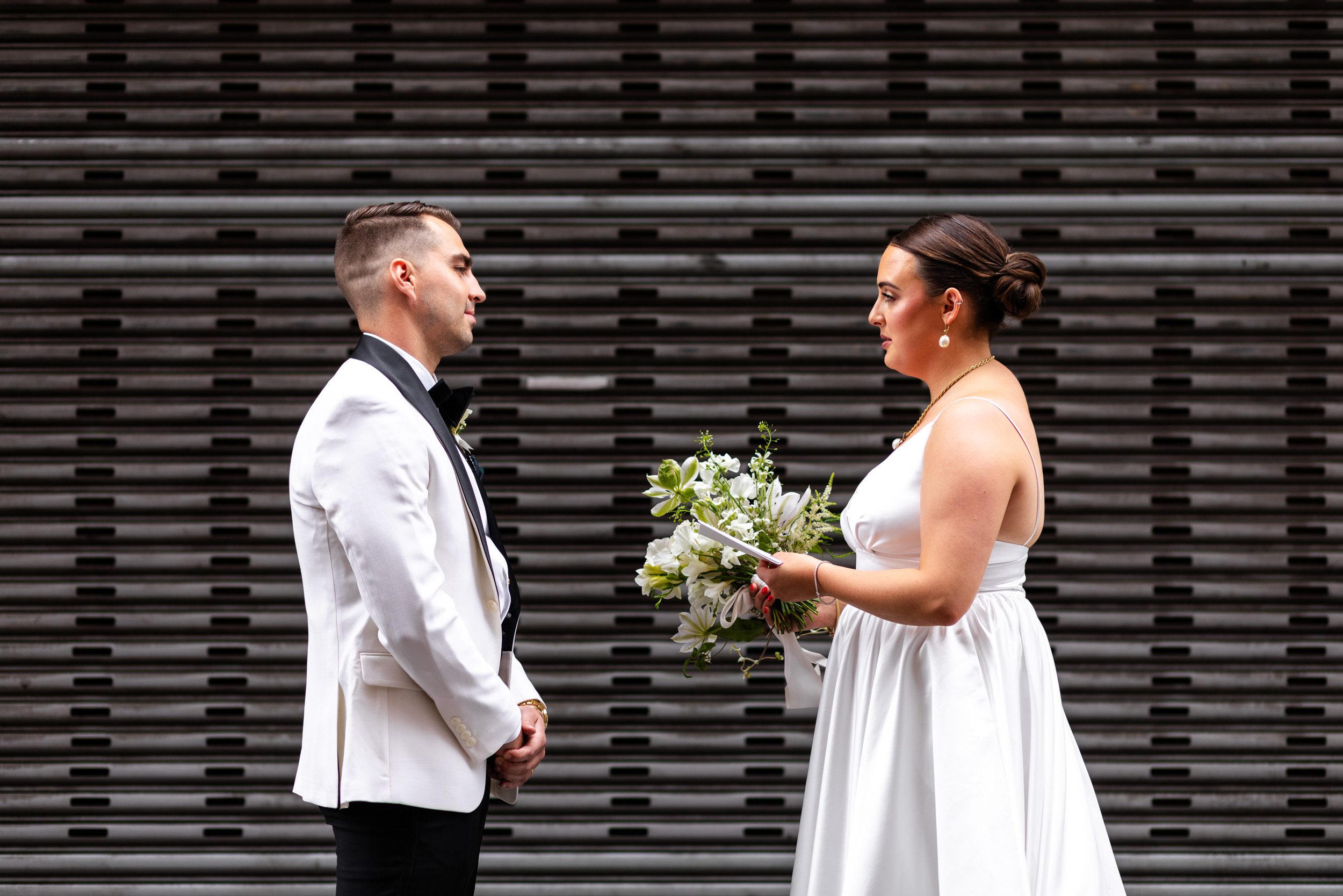 Bride and groom, during first look and private vows in elegant black tie, wedding outside of the Alexis Hotel