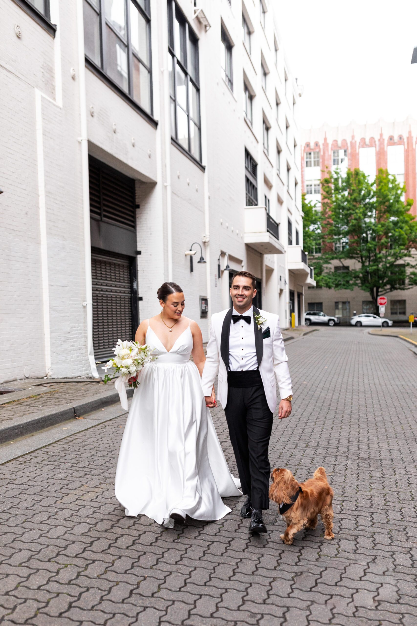 Bride and groom walking with their dog next to the Alexis Hotel where they got ready for their downtown Seattle wedding.
