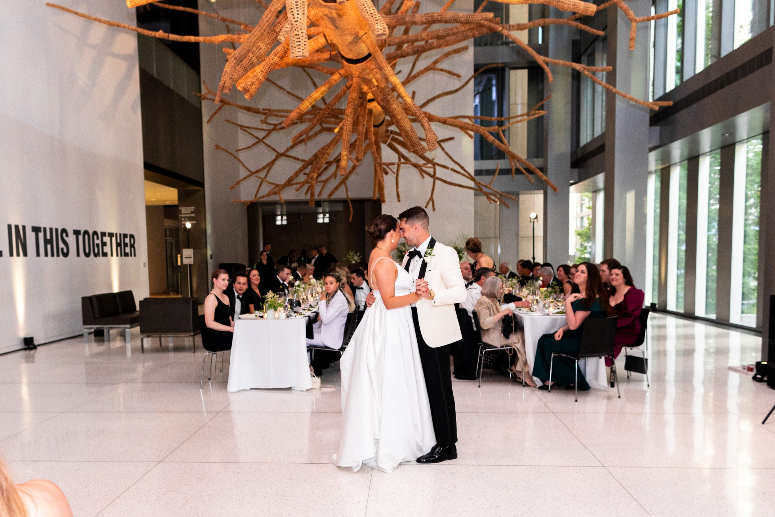 Bride and groom, sharing their first dance underneath the tree sculpture at the Seattle Art Museum during their downtown Seattle wedding