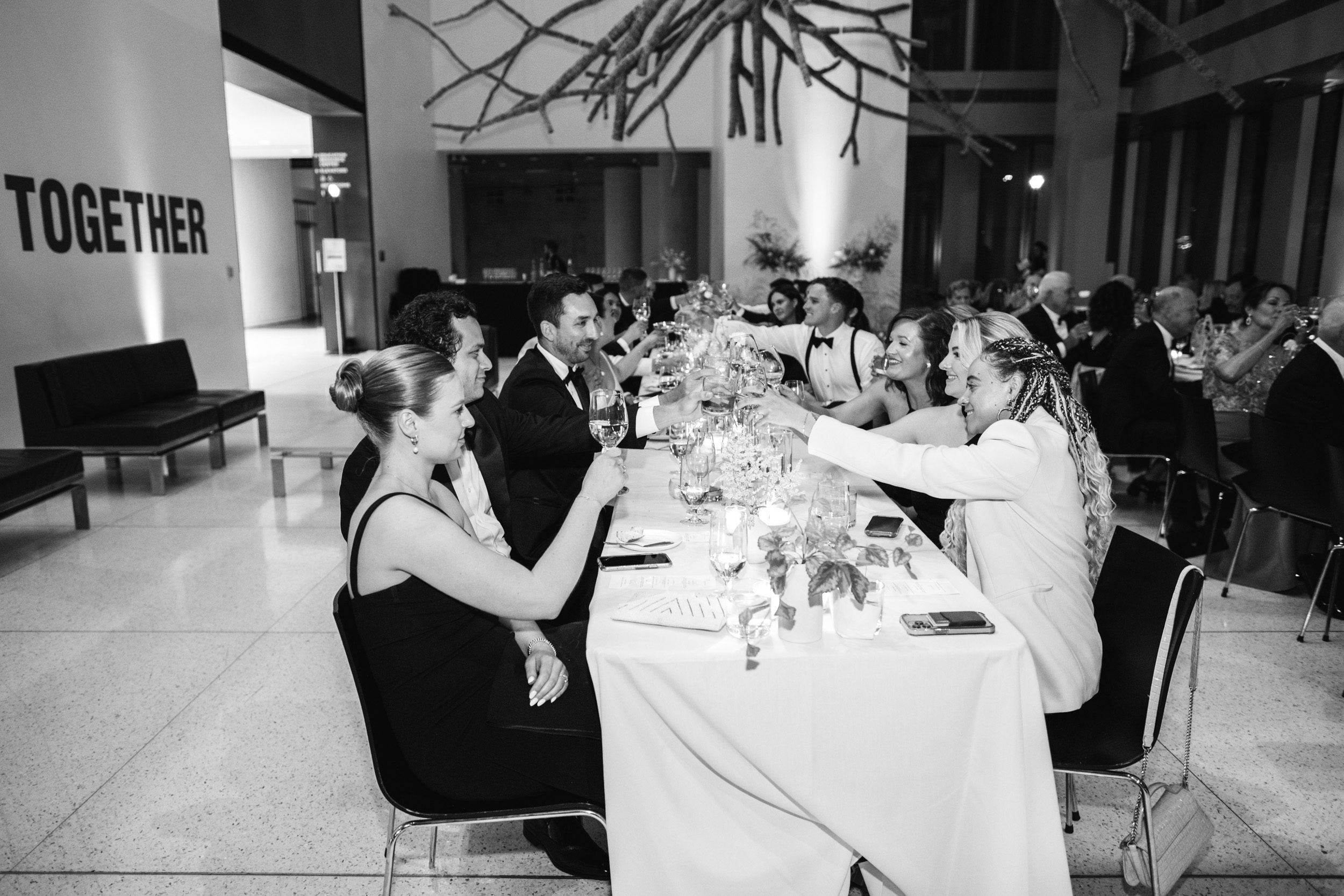 Black and white photo of guests clinking their glasses and celebrating after speeches at the Seattle Art Museum wedding in downtown Seattle.