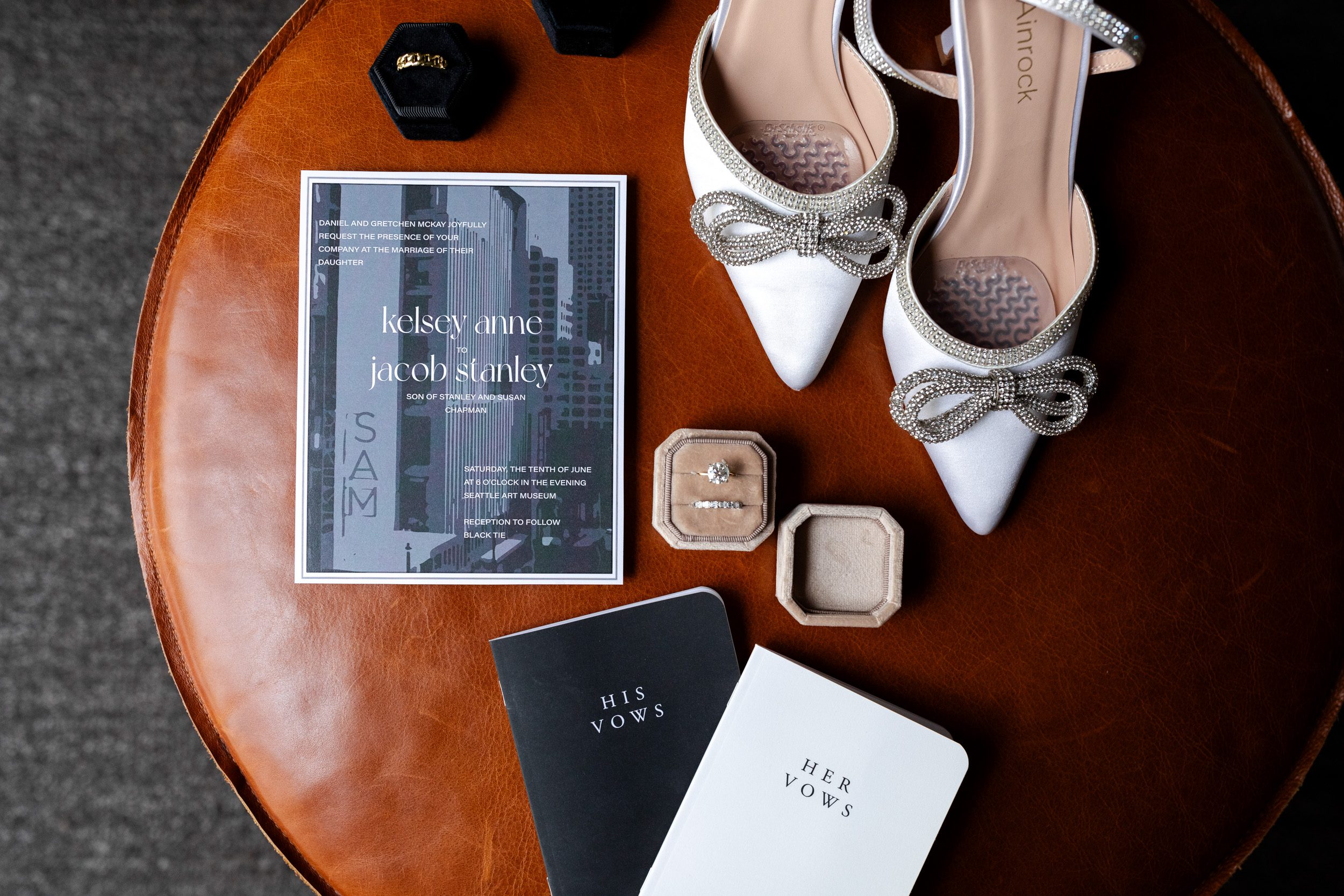 Detail photo of the bride's shoes, rings, invitation and vow book during getting ready at The Alexis Hotel.
