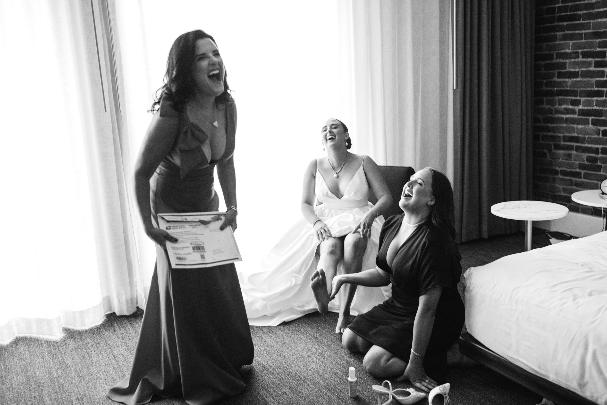Black and white photo of bride with bride sister, and mother of the bride, during getting ready and laughing at the Alexis hotel.