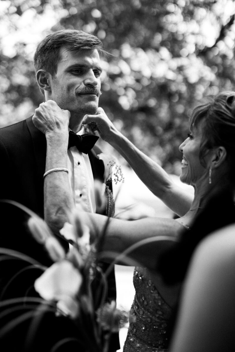 Groom's mom fixing groom's bowtie ahead of Villa Academy Seattle wedding ceremony