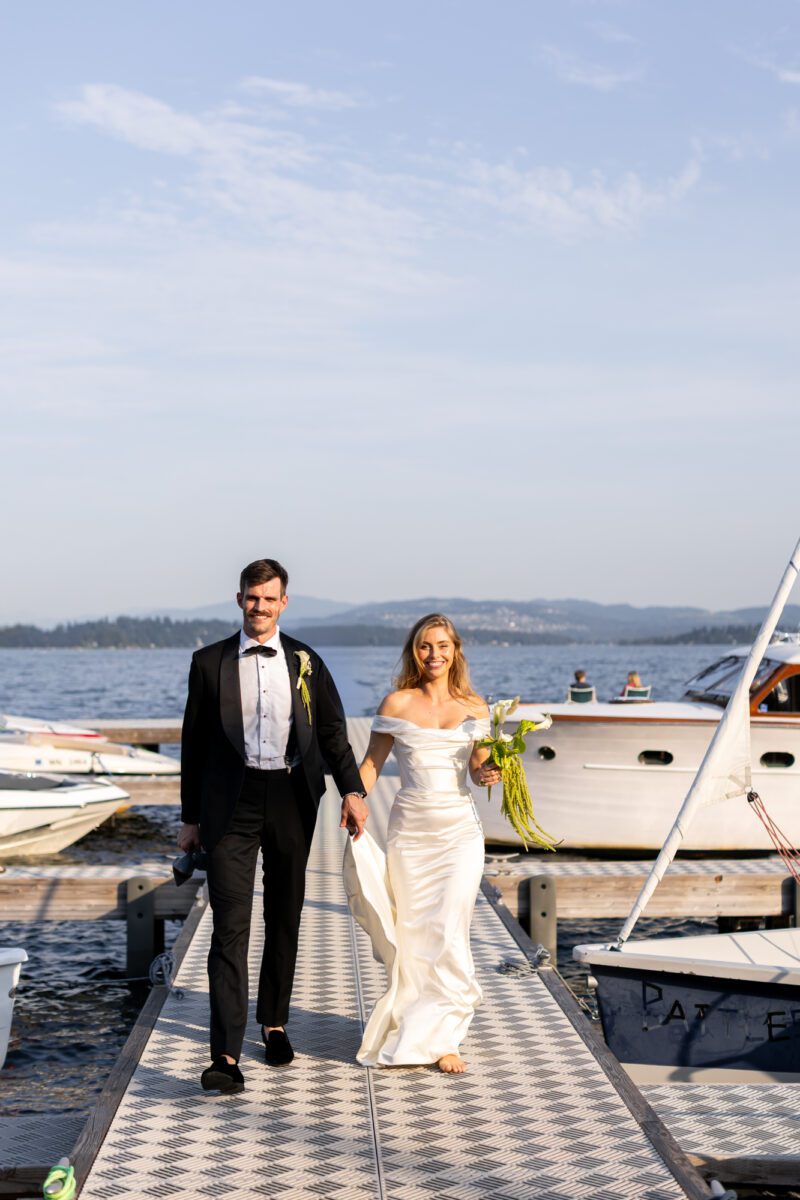 Bride and groom exiting boat and entering cocktail hour outside with guests at Seattle Tennis Club on lawn