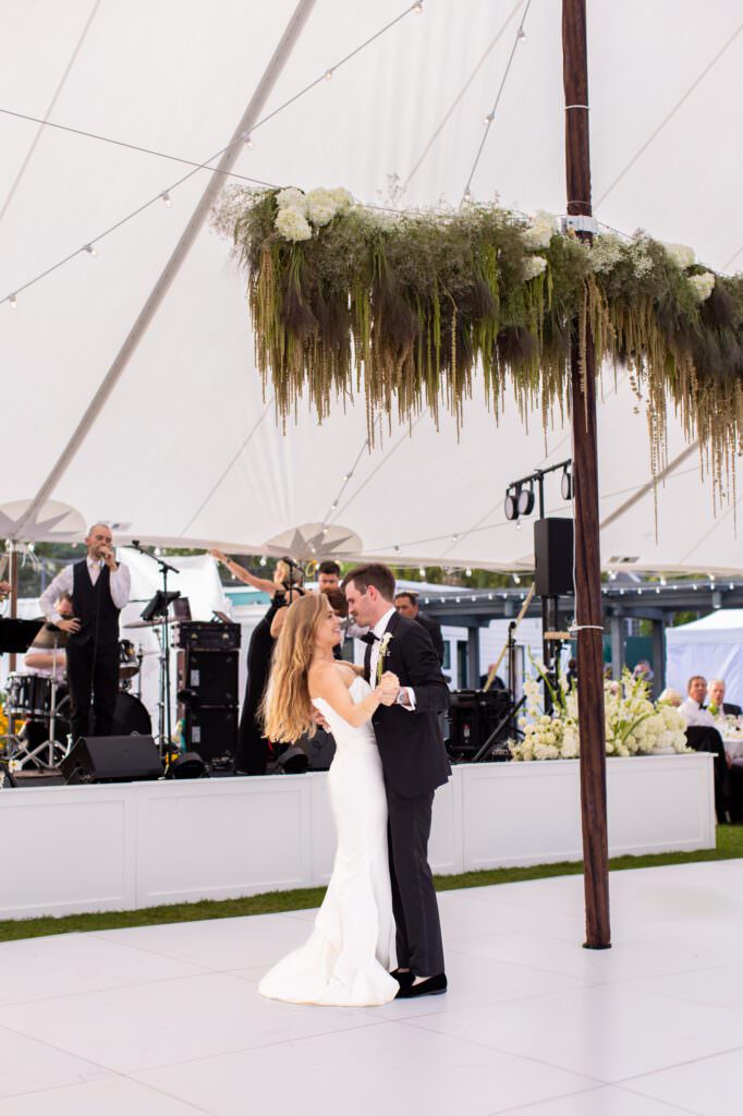 Bride and groom first dance in tent under hanging florals