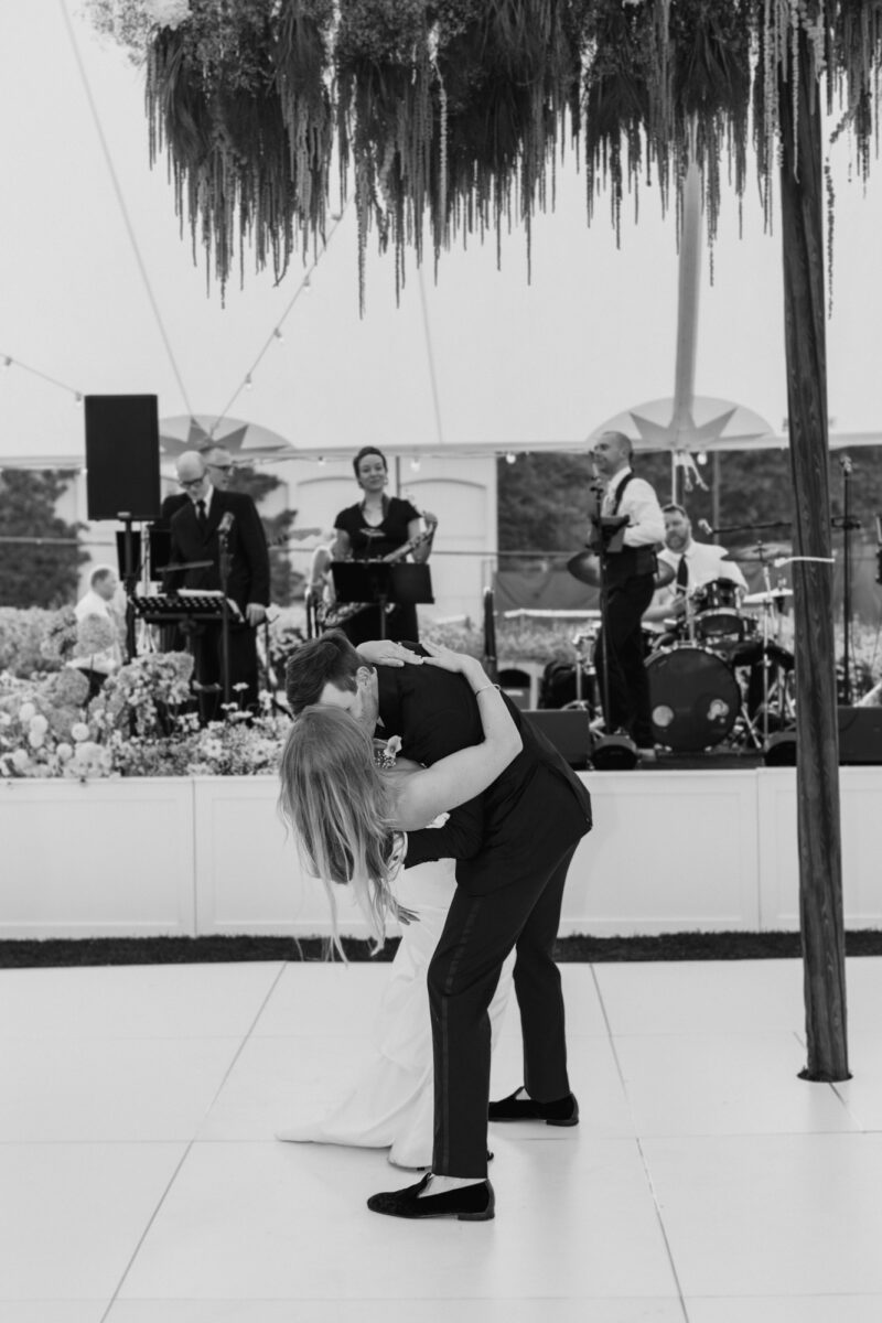 Bride and groom first dance in tent under hanging florals