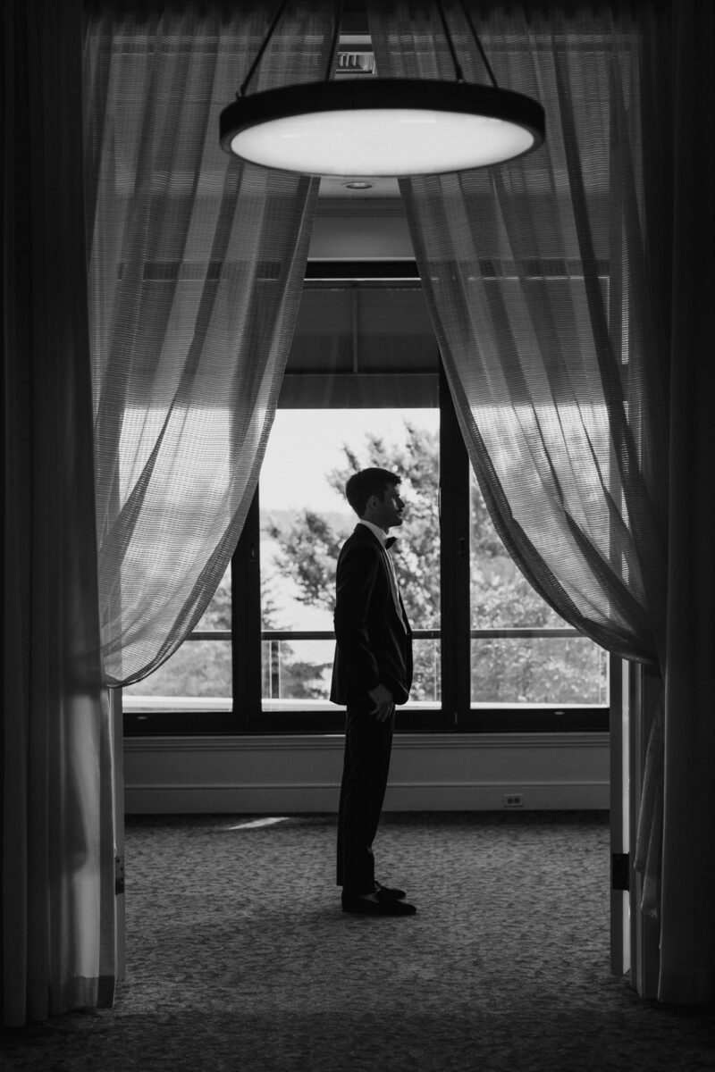 Black and white photo of groom before first look with bride
