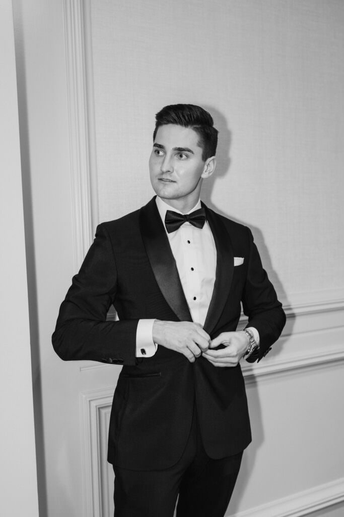 Black and white close up photo of groomsmen during getting ready photos with black suit and bow tie