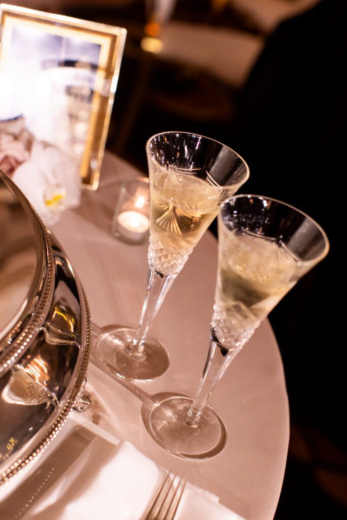 Close up of champagne glasses on cake table for bride and groom during cake cutting.