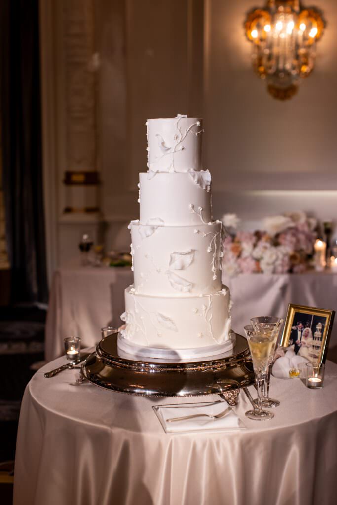 White tiered wedding cake with intricate leaf design, four tiered wedding cake during downtown Seattle wedding reception at the Fairmont Olympic Hotel.