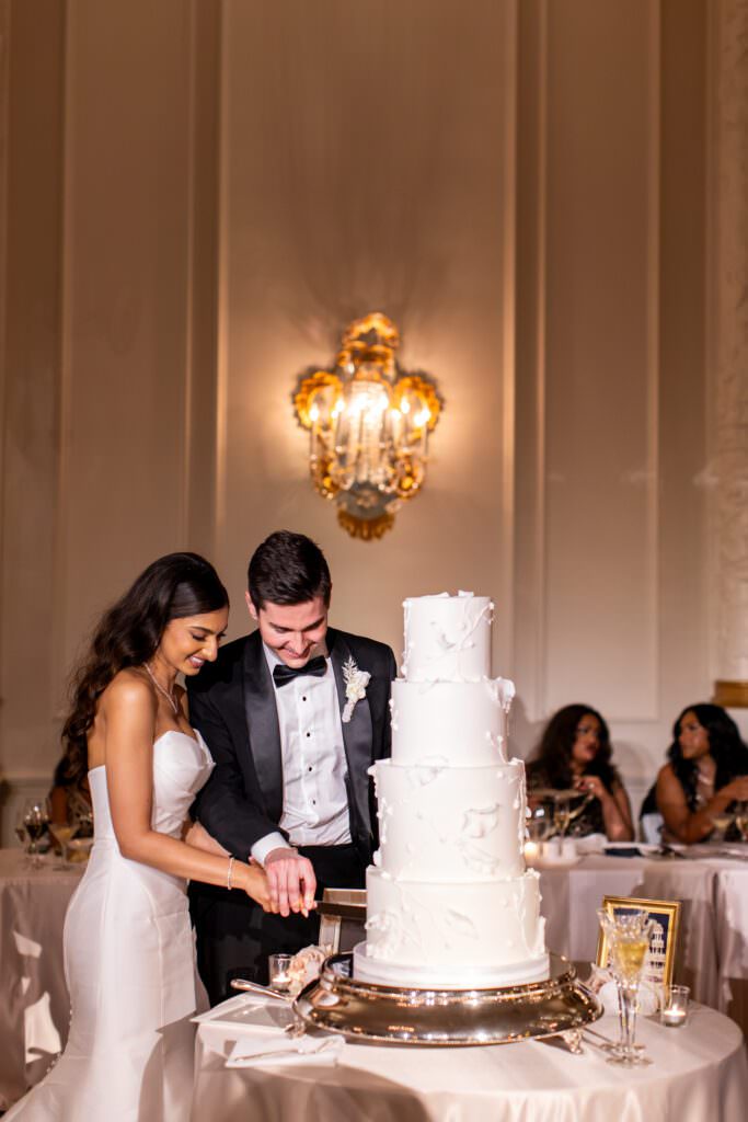 Bride and groom cutting tiered wedding cake during black tie luxury wedding at the Fairmont Olympic Hotel Seattle