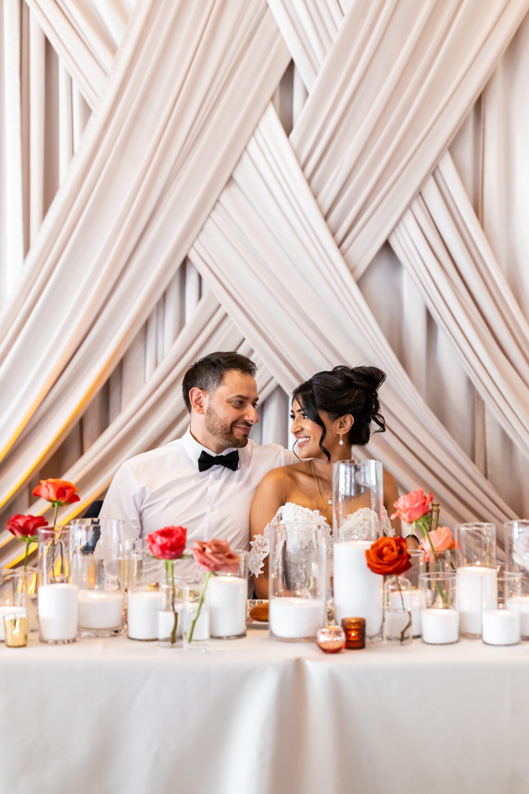 Bride and groom at sweetheart table during downtown Seattle wedding with draping behind them