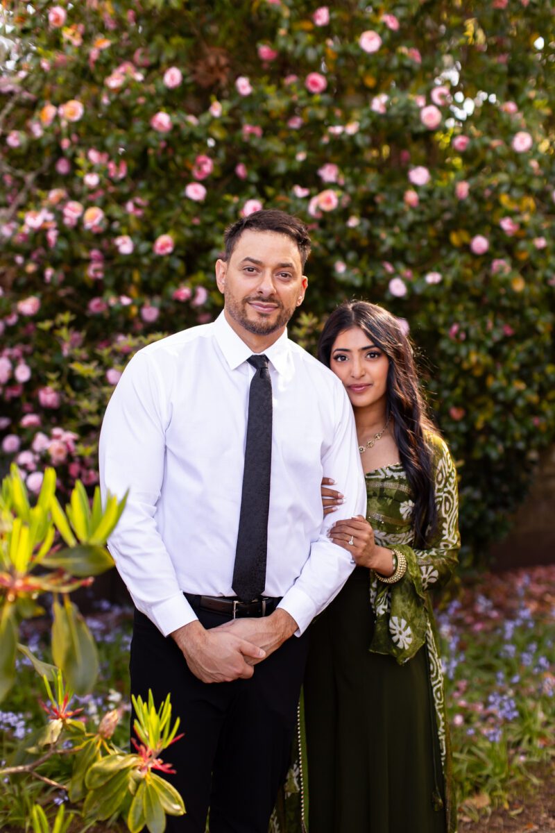 bride in lehenga and groom posing outside in the garden of the washington state capitol for their engagements