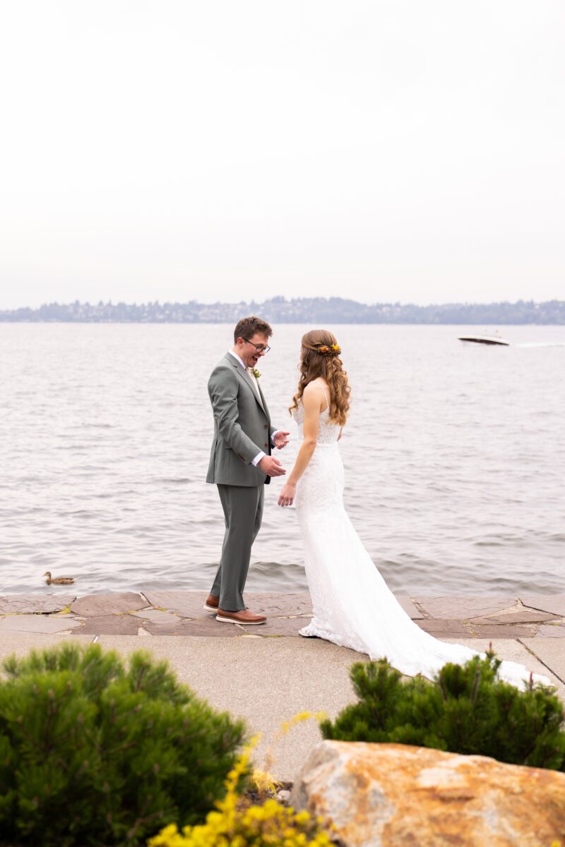 Bride walking up to groom for first look on Lake Washington in Seattle with boat in the background