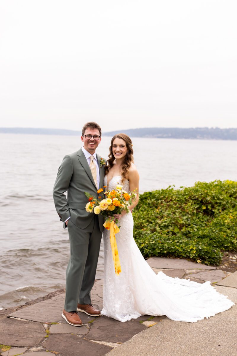 Bride and groom Portraits on Lake Washington at the Woodmark hotel and still spot in Kirkland. Groom, sage, green suit, yellow, and orange wedding flowers.