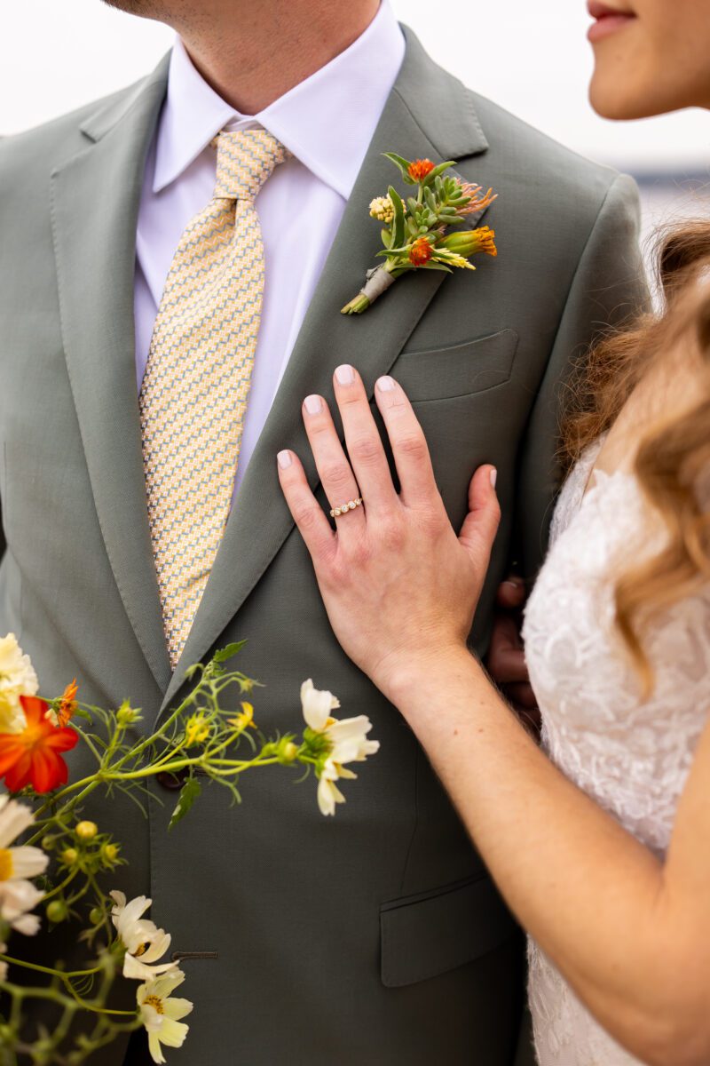 Bride and groom Portraits on Lake Washington at the Woodmark hotel and still spot in Kirkland. Groom, sage, green suit, yellow, and orange wedding flowers.