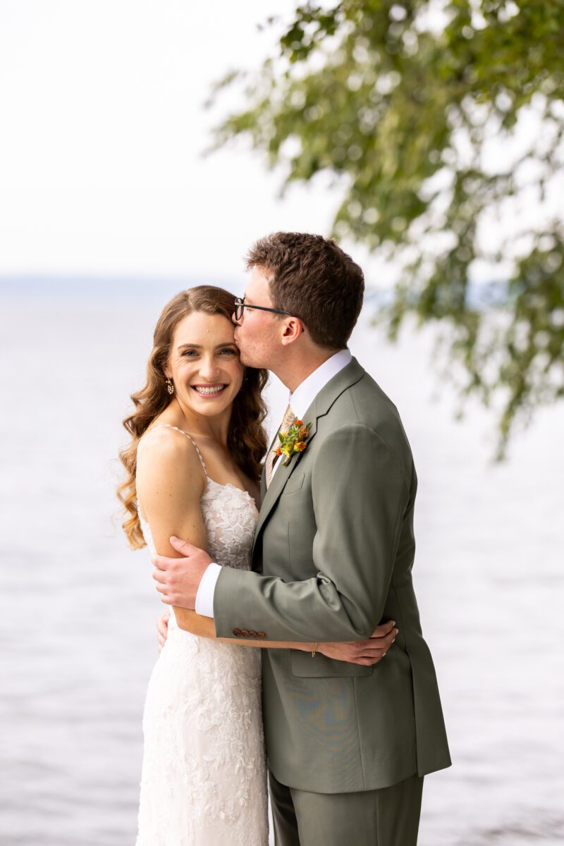 Bride and groom Portraits on Lake Washington at the Woodmark hotel and still spot in Kirkland. Groom, sage, green suit, yellow, and orange wedding flowers.