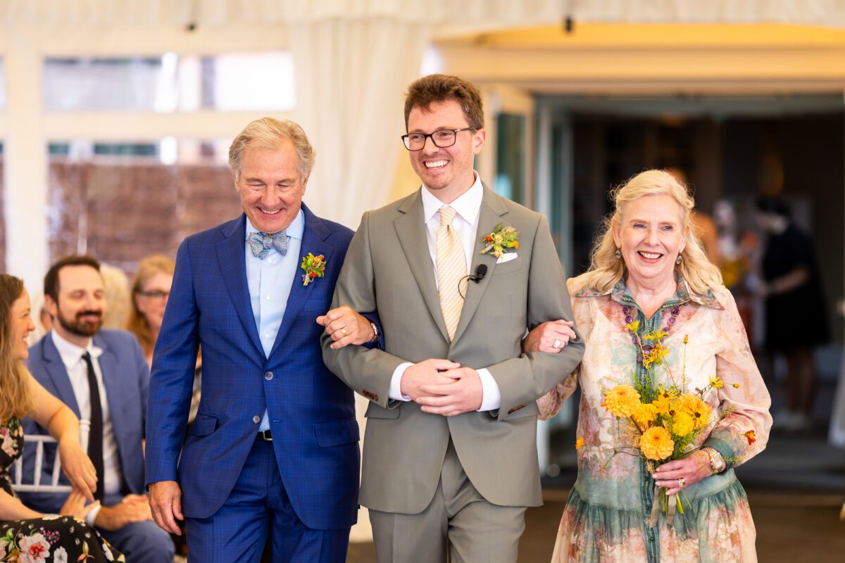 Groom, walking down the aisle with his parents in Seattle tent, wedding ceremony