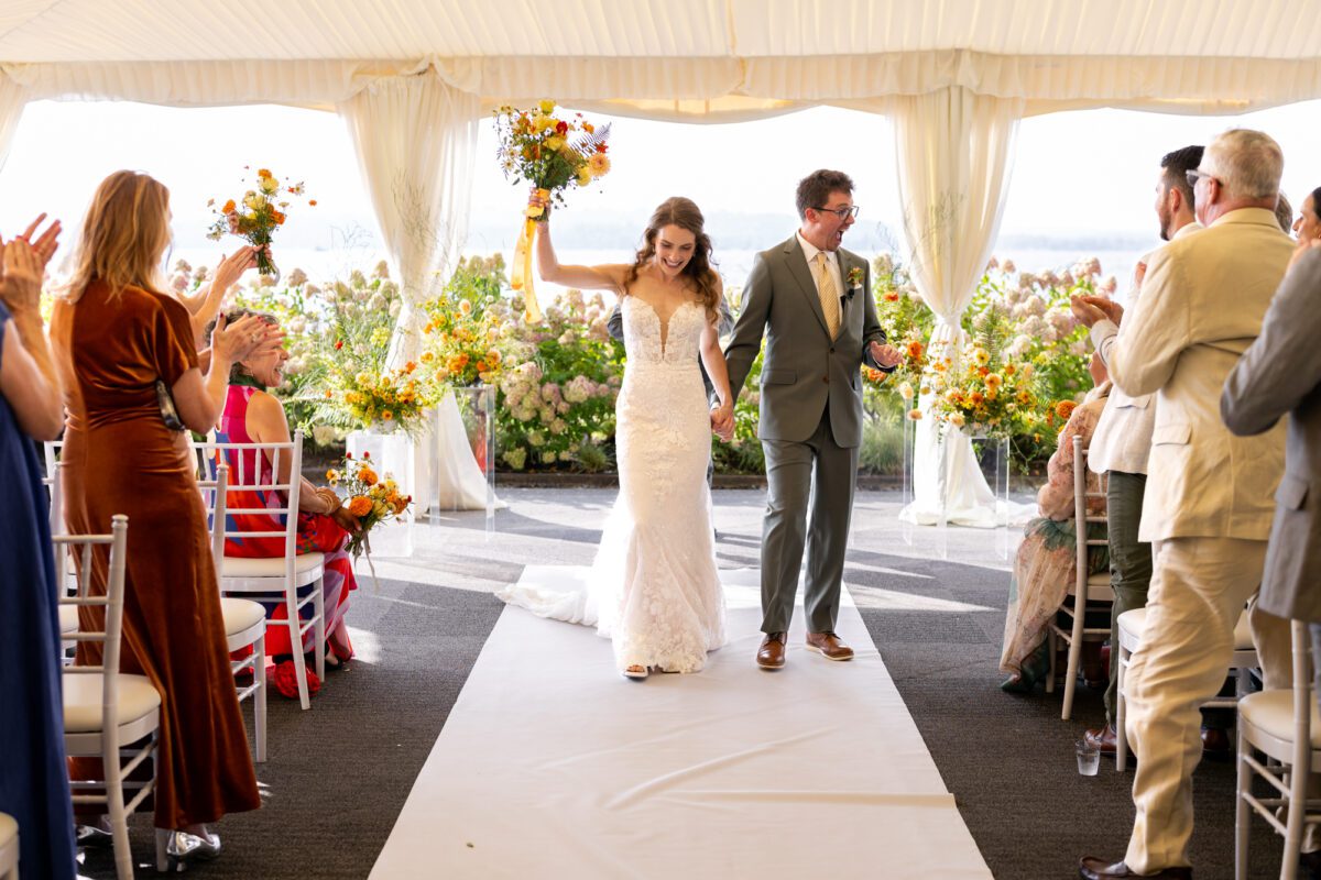 Bride and groom during outdoor tent, wedding ceremony at the Woodmark hotel, and still spa on Lake Washington, exiting ceremony