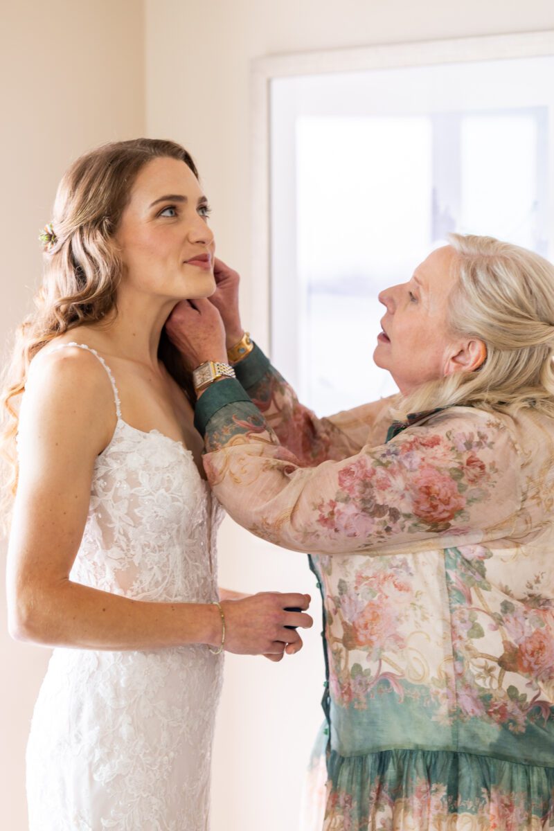 Grandmother of the bride helping Bride get ready, grandma putting on special earrings on Bride