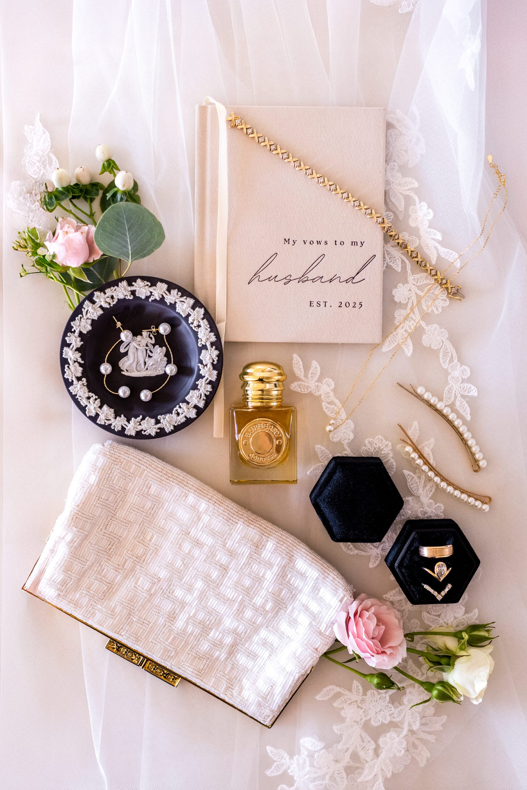 White, pink, and green wedding details displayed on a wedding veil. Wedding flat lay photo, wedding detail shot.