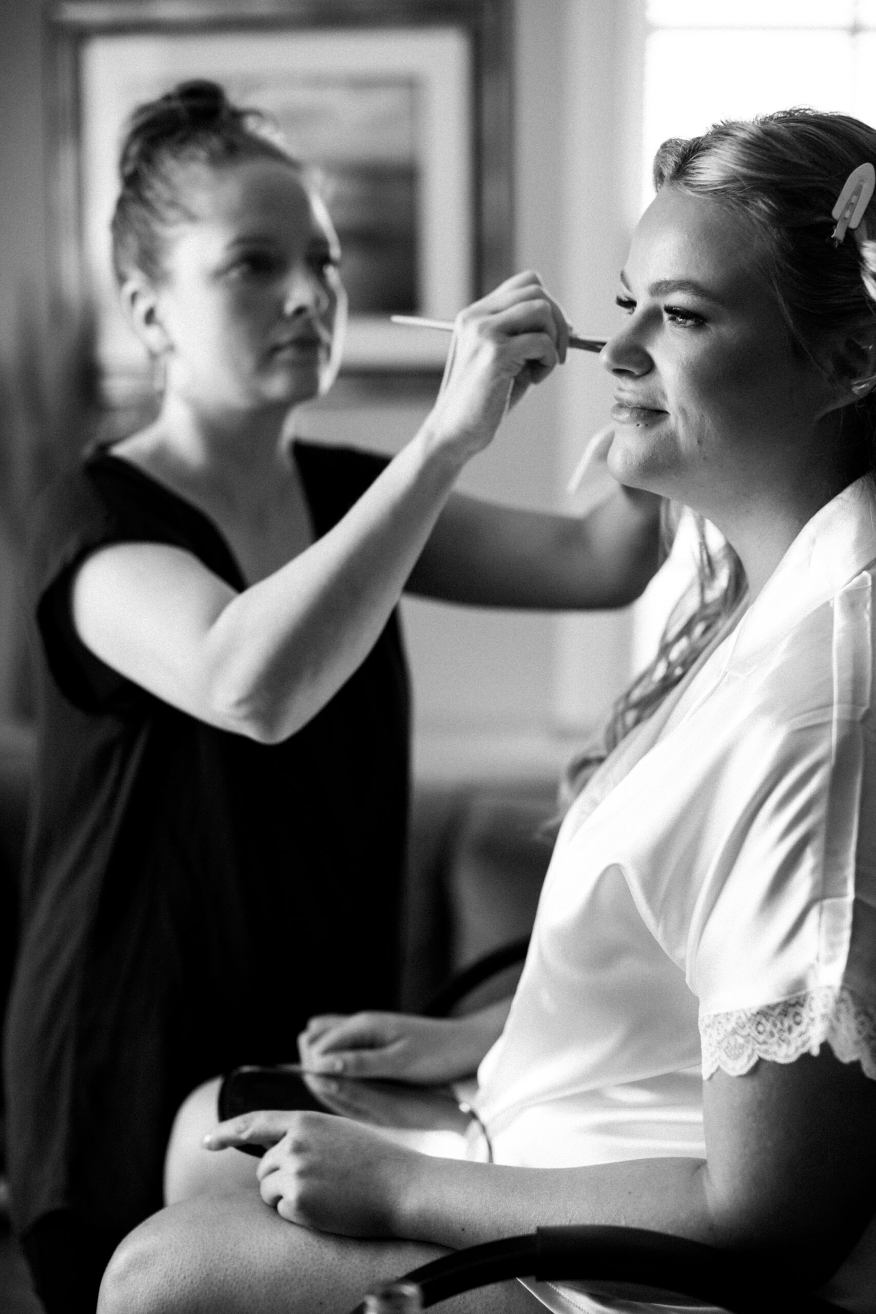Black and white image of bride getting her makeup done at the Hotel Leo across the street from the ceremony venue