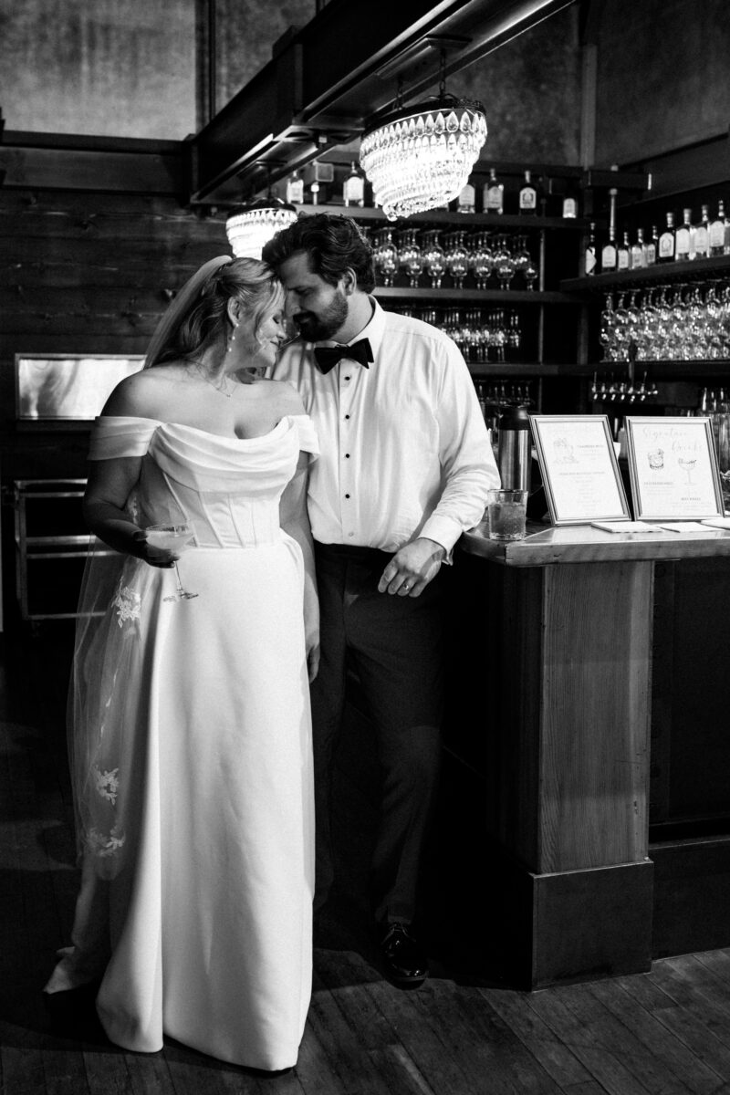 bride and groom at bar holding drinks during cocktail hour for chuckanut bay distillery wedding