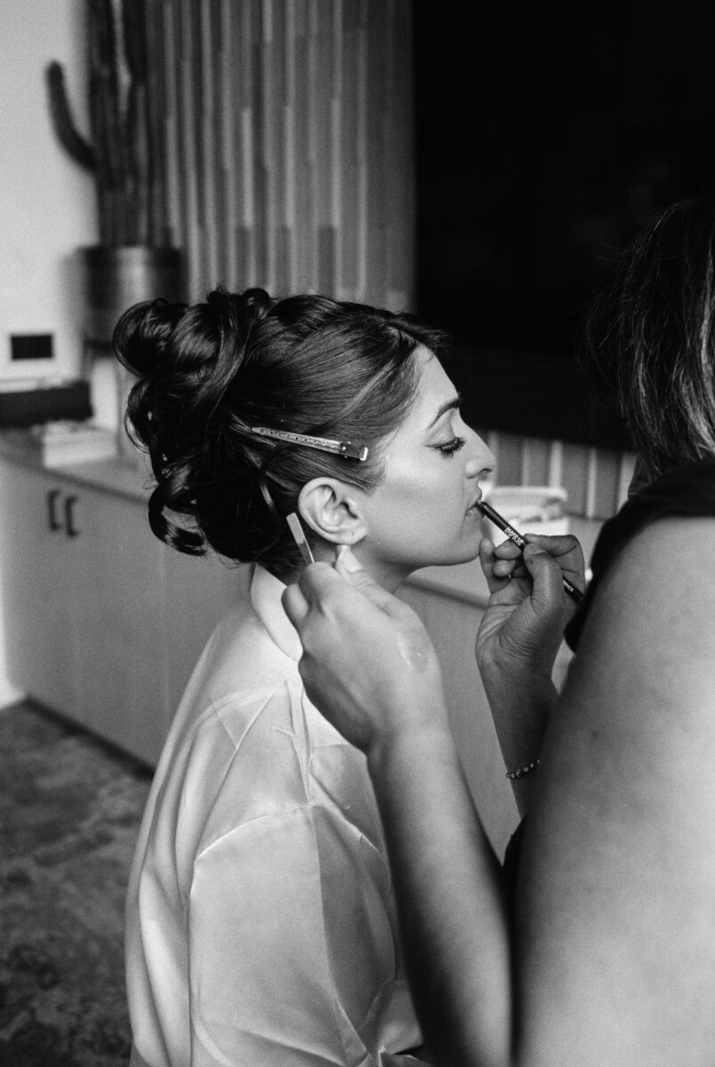 Black and white image of bride getting makeup done for Indian wedding in Seattle
