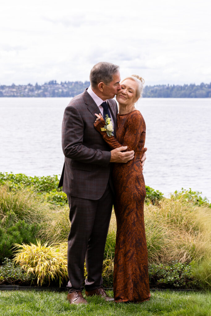 Parents of the groom kissing near the water