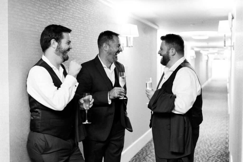 Groomsmen laughing in the hallway of the Woodmark Hotel before getting ready