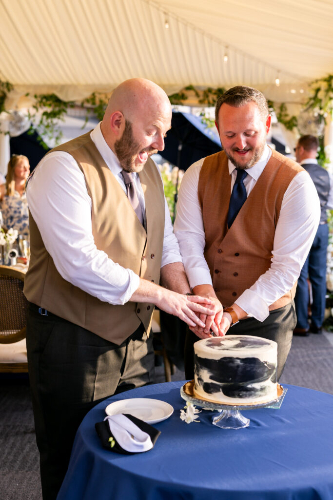 Two grooms cutting wedding cake