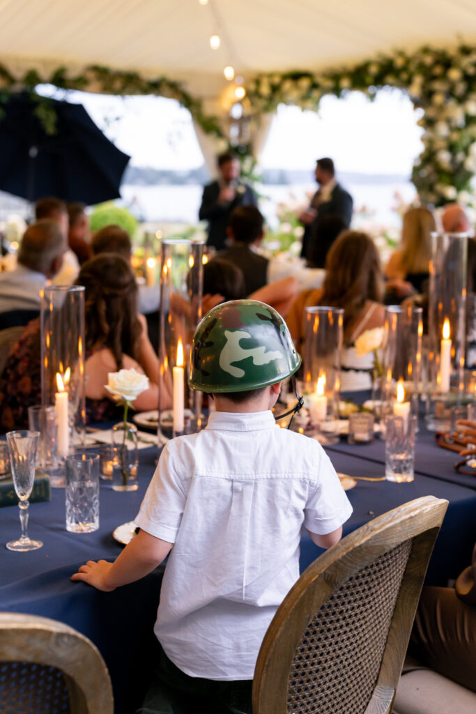 Little boy in army helmet listening to wedding speeches