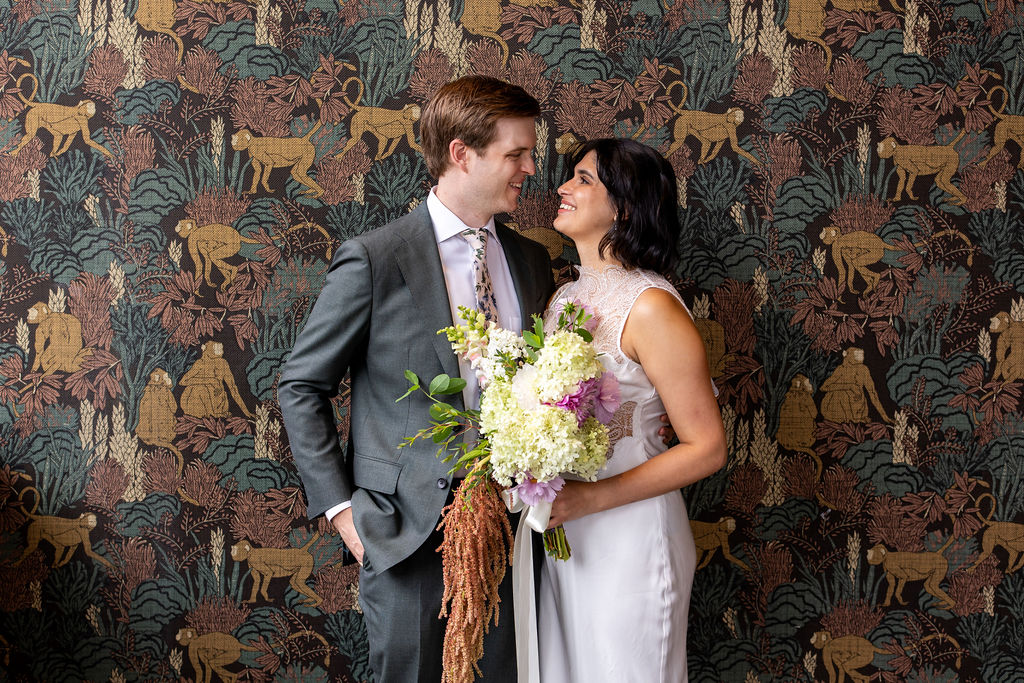 bride and groom snuggled against wall paper