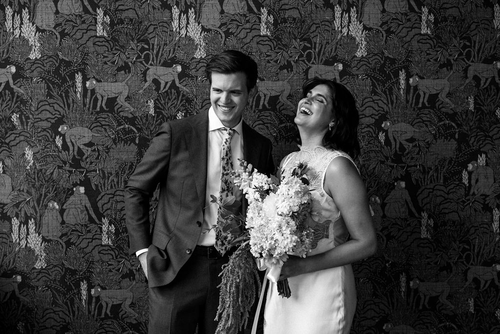 bride and groom snuggled against wall paper